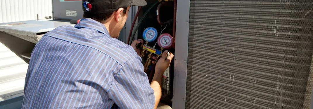 HVAC technician servicing a condenser unit in Southfield